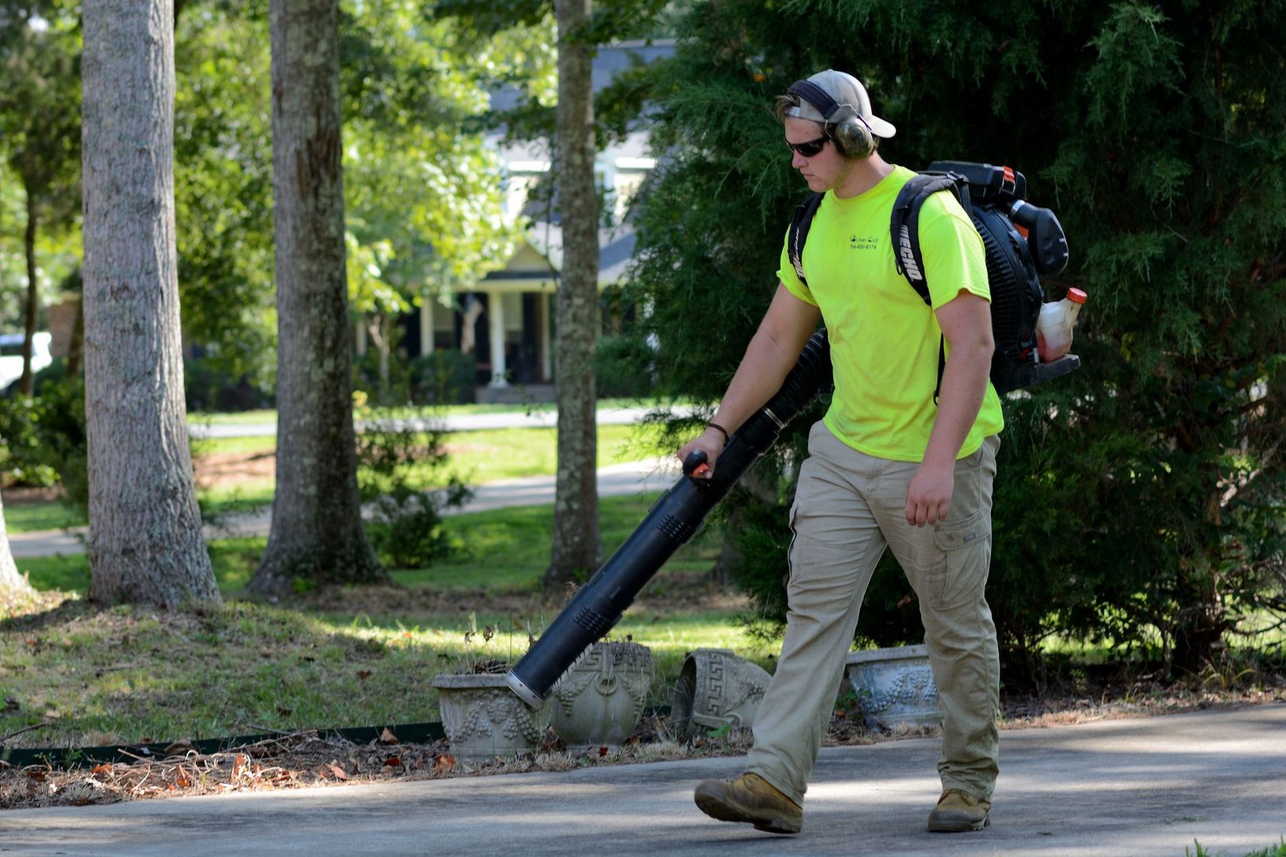Landscaper clearing a driveway with a backpack blower